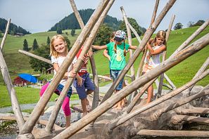 Kinder balancieren auf einem Baumstamm.