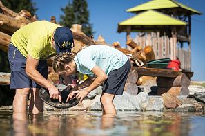 Vater und Kind durchsuchen flaches Wasser nach Steinen oder Gold.