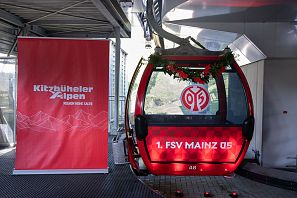 Seilbahn mit rotem Design und Vereinslogo von FSV Mainz 05, dekoriert mit Tannenzweigen.