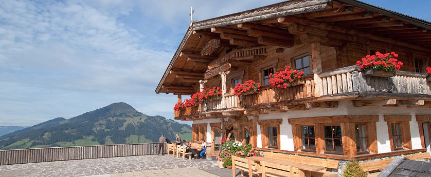 Altes Bauernhaus mit roten Blumen am Balkon.