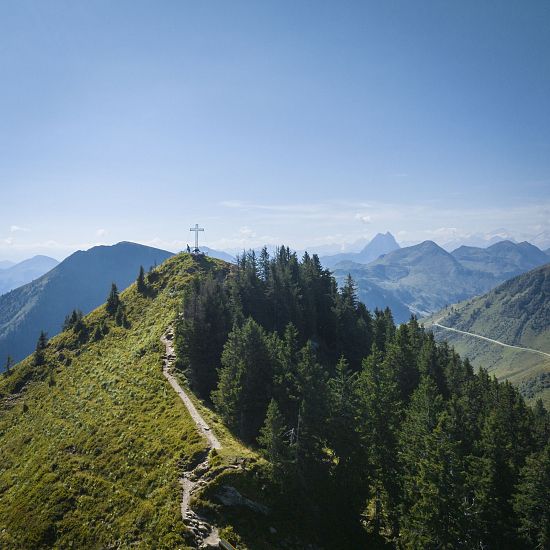 Ausblick auf das Gipfelkreuz und die umliegenden Berge.