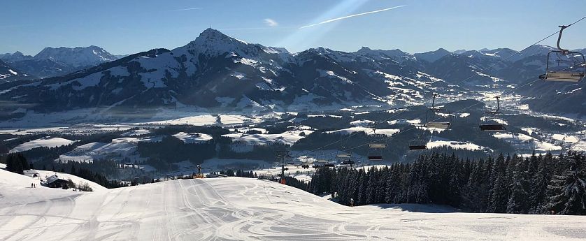 Talabfahrt Astberg mit präparierter Piste, Sonnenschein und Blick auf das verschneite Tal vor dem Kitzbühler Horn