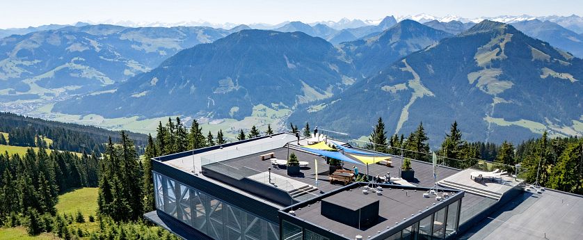 Riesen-Panorama-Aussichtsplattform mit Glasfassade und Dachterrasse, umgeben von Bergen und Wäldern.