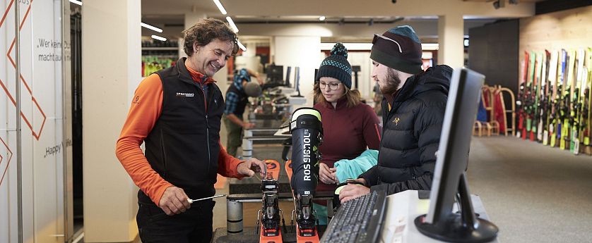 Gäste werden von einem Mitarbeiter zu Skiern beraten.