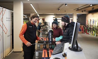 Gäste werden von einem Mitarbeiter zu Skiern beraten.