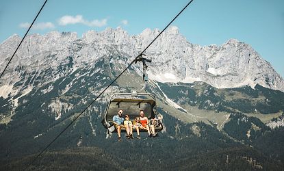Leute in einem Sessellift vor dem Wilden Kaiser.