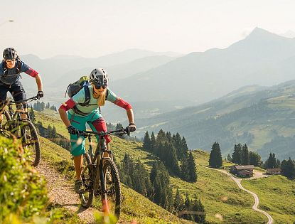 Zwei Mountainbiker im Sommer mit Rucksack, Helm und Brille am Wiegalmtrail mit leicht vernebeltem Panoramablick