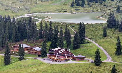 Brechhornhaus in der SkiWelt Wilder Kaiser Brixental mit Speichersee, umgeben von grünen Almwiesen und Wäldern.