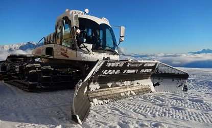 Eine weiße Pistenraupe im Schnee.
