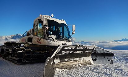 Eine weiße Pistenraupe im Schnee.