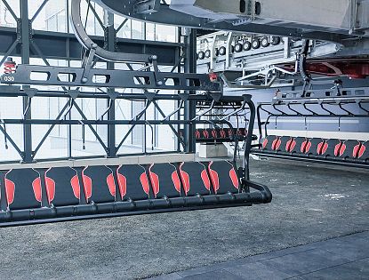 Ein leerer Skilift mit roten Sitzen, der bereit für den Einsatz in einer modernen Bergstation ist.