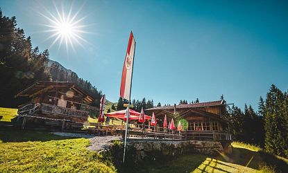 Die Frankalm in Brixen mit Sonnenterrasse und Tiroler Fahne, idealer Einkehrschwung für Wanderer und Mountainbiker im Sommer