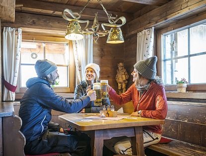 Freunde auf Hütte beim Anstoßen und Kaiserschmarrn essen