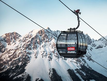 Schwarze Gondel Hartkaiserbahn in Ellmau mit dem verschneiten Wilden Kaiser im Hintergrund