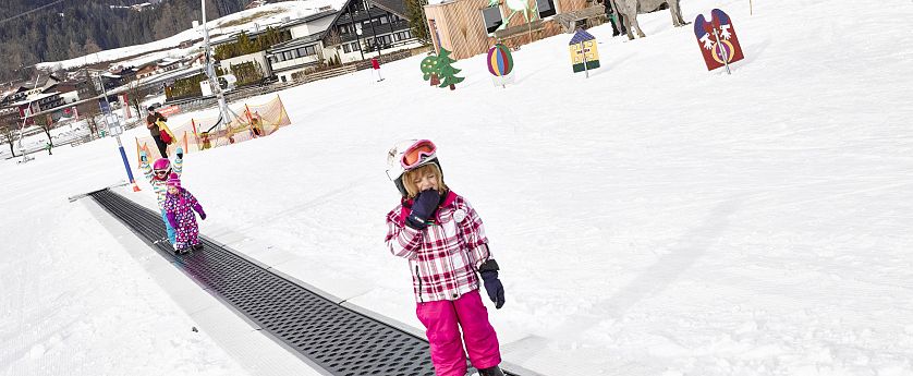 Zwei Kinder stehen mit Ski auf dem Zauberteppich am Übungsgelände auf der Hexenwiese