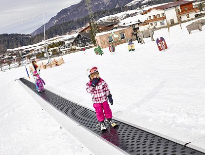 Zwei Kinder stehen mit Ski auf dem Zauberteppich am Übungsgelände auf der Hexenwiese