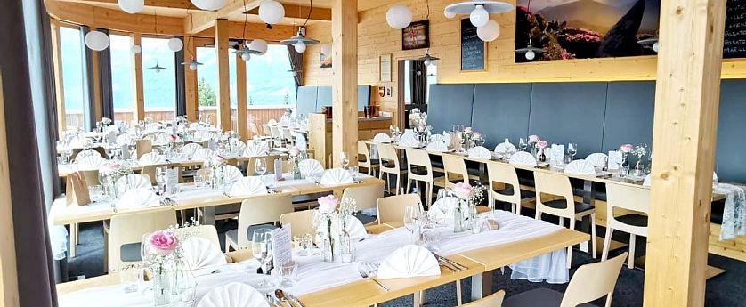 Modernes, lichtdurchflutetes Restaurant mit Holzelementen, weißen Papierlampions und elegant gedeckten Tischen für eine Feier