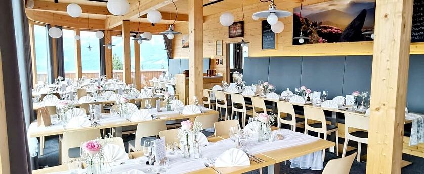 Modernes, lichtdurchflutetes Restaurant mit Holzelementen, weißen Papierlampions und elegant gedeckten Tischen für eine Feier
