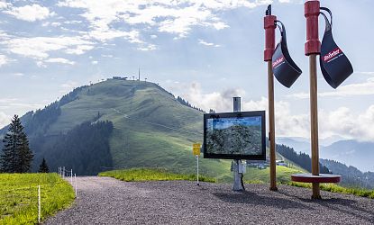 Panoramablick von der Kleinen Salve Bergstation auf den Berg Hohe Salve mit digitaler Wanderkarte und grünen Sommerwiesen.