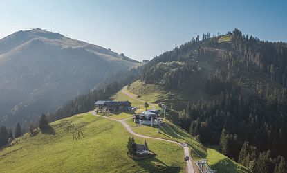 Sommerliche Berglandschaft mit Seilbahnstation und Kraftalm in Itter, umgeben von Wäldern und Gipfeln