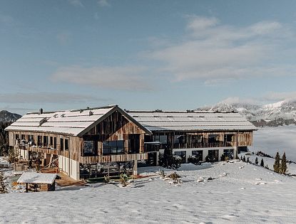Kraftalm mit verschneitem Dach und Blick auf die Alpen.