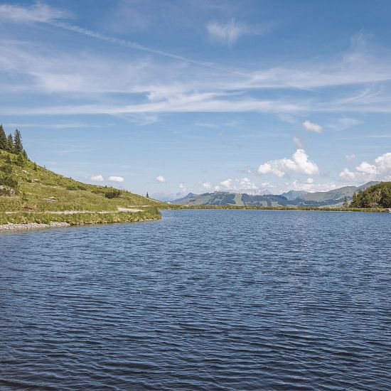 Ein klarer See inmitten von Bergen und unberührter Natur.