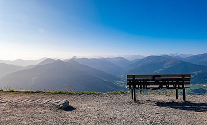 Aussichtsbank auf der Hohen Salve mit Panoramablick über die Tiroler Alpen und sonnige Berglandschaft