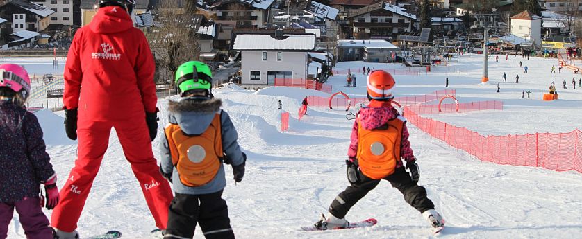 Kinder lernen Skifahren mit einem Skilehrer.