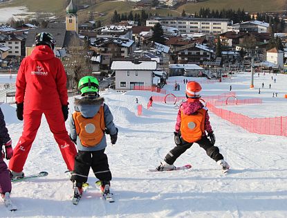 Kinder lernen Skifahren mit einem Skilehrer.