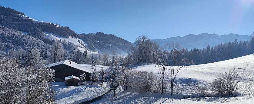 Blick auf eine Winterlandschaft und eine alte Hütte.