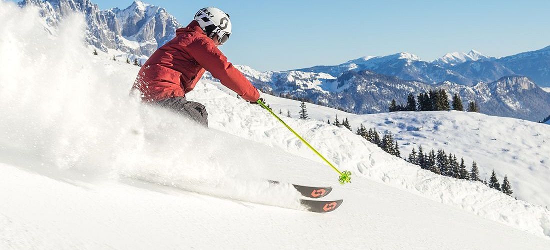 Skifahrer flitzt die Piste hinab in der SkiWelt Wilder Kaiser-Brixental.