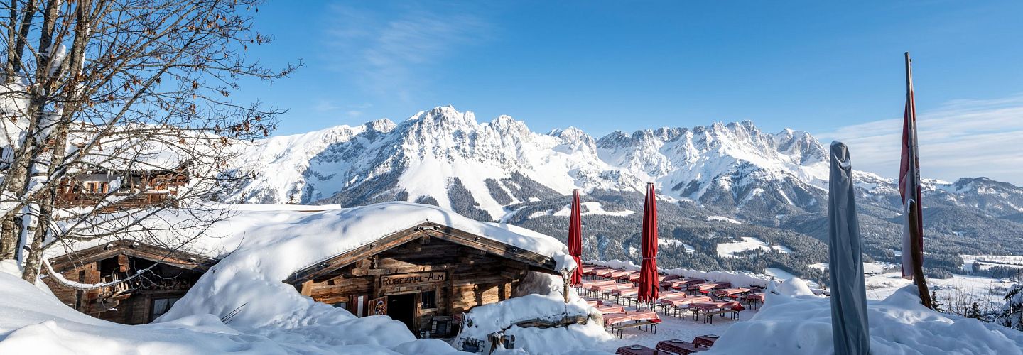 Beschneite Hütte am Berg mit einem Alpenpanorama.
