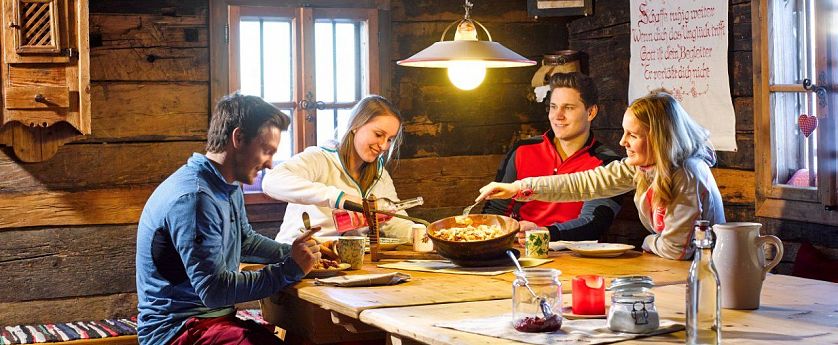 Freunde essen zusammen in einer urigen Almhütte.