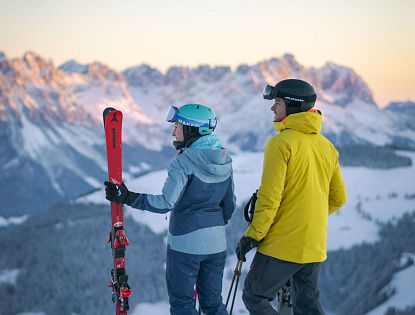 Skifahren bei Sonnenaufgang Bergspitzen Sonnenstrahlen Morgenrot Early Bird auf Piste SkiWelt