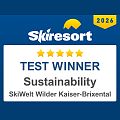 Logo ośrodka narciarskiego z nagrodą "Zwycięzca testu" w kategorii zrównoważony rozwój, z nazwą SkiWelt Wilder Kaiser-Brixental.