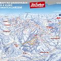 Panorama-Skikarte zeigt Skipisten, Skilifte und Bergmarkierungen in einer verschneiten Berglandschaft. Namen und Routen sind farblich hervorgehoben. Ideal für Wintersport.