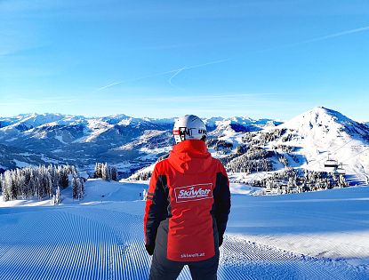 SkiWelt Mitarbeiter vor traumhafter Bergkulisse.