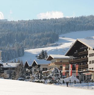 Verschneites Sporthotel Tirolerhof in Itter im Winter, rauch steigt aus dem Schornstein auf