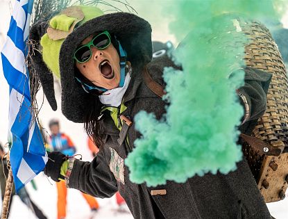 Hexe mit grünem Rauch in der Hand beim Skifahren.