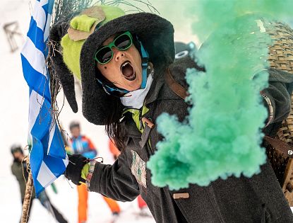 Hexe mit grünem Rauch in der Hand beim Skifahren.