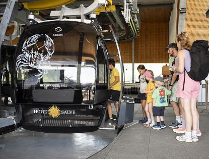 Familie an der Seilbahnstation, bereit zum Einsteigen in die Gondel.
