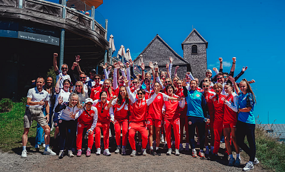 Sportliche Frauen in roten Uniformen feiern vor historischen Gebäuden.