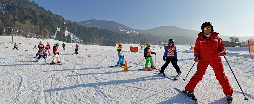 Kinder fahren ihrem Skilehrer brav hinterher.