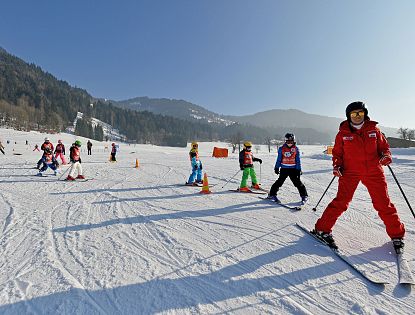 Kinder fahren ihrem Skilehrer brav hinterher.
