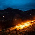 Brennende Bergfeuer leuchten bei Einbruch der Nacht im Brixental in Tirol und formen eindrucksvolle Motive am Hang.