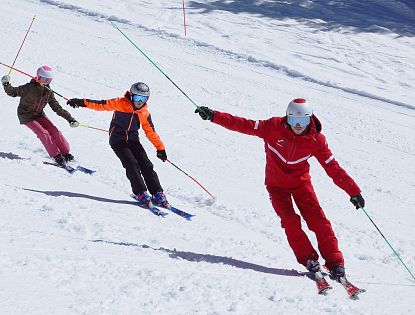 Skilehrer mit zwei Kindern beim Techniktraining auf der Skipiste in der Skischule Going – Skifahren lernen in Tirol
