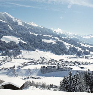 Ortschaft Westendorf verschneit im Winter mit Berglandschaft im Hintergrund