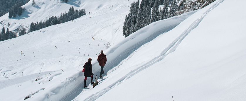 Zwei Winterwanderer die durch die SkiWelt Ellmau-Going wandern.
