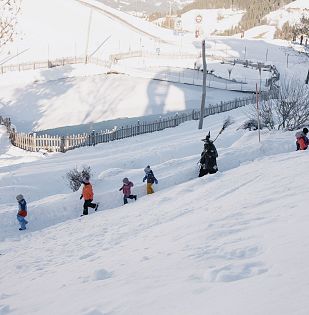 Die Hexen gehen mit den Kindern durch den verschneiten Winterwanderweg.