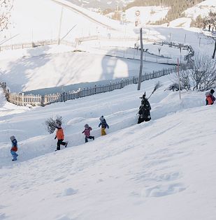 Die Hexen gehen mit den Kindern durch den verschneiten Winterwanderweg.